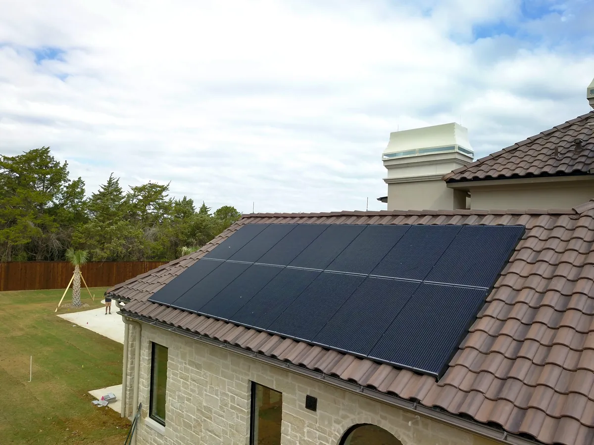Black solar panels on a tile roof of a stone home